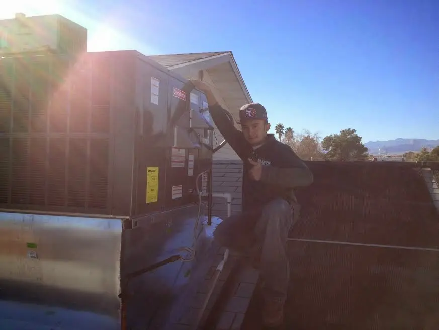 HVAC technician performing Air Duct Cleaning on a rooftop unit in Salem